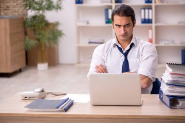 Genç bir erkek çalışan ve ofiste bir sürü iş var.