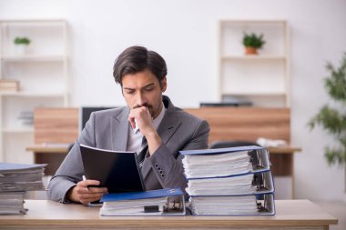 Ofisteki aşırı işten memnun olmayan genç bir erkek işçi.