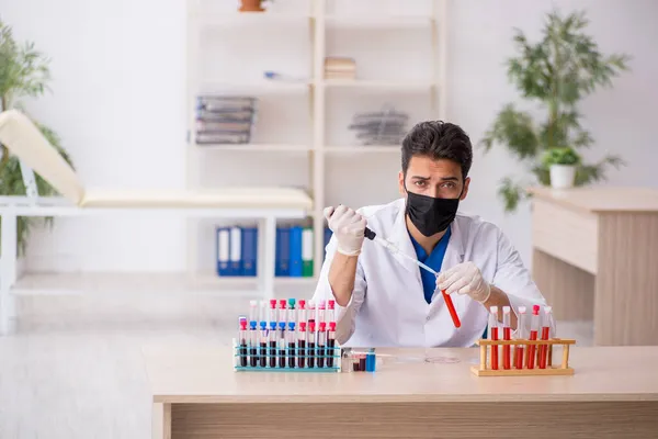 Молодий чоловічий біохімік тестує зразки крові в пандемічній концепції — стокове фото