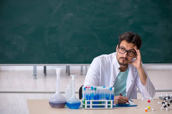 Молодой химик перед школьной доской — стоковое фото
