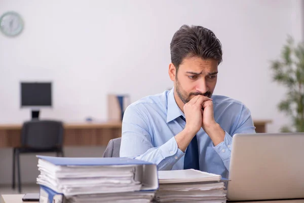 Ung manlig anställd och för mycket arbete på kontoret — Stockfoto