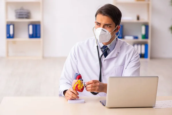 Genç erkek doktor kardiyolog pand sırasında klinikte çalışıyor. — Stok fotoğraf