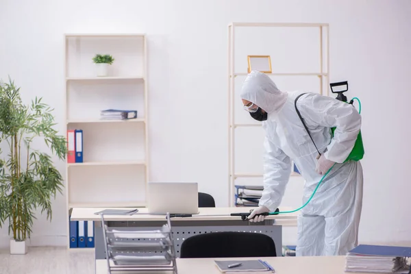 Jovem empreiteiro masculino desinfetando escritório durante pandemia — Fotografia de Stock