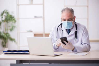 Klinikte çalışan yaşlı erkek doktor.