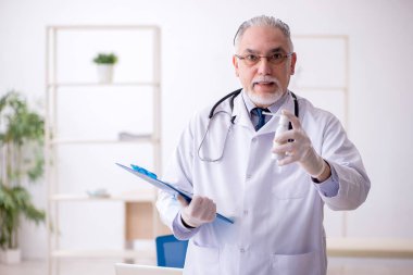 Klinikte çalışan yaşlı erkek doktor.