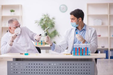 Salgın sırasında laboratuvarda çalışan iki erkek kimyager.