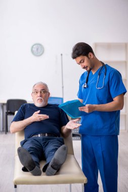 Yaşlı adam genç erkek doktoru ziyaret ediyor.