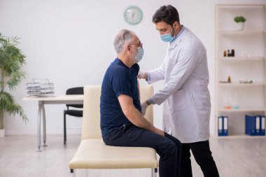 Yaşlı bir erkek hasta aşıyla genç bir doktoru ziyaret ediyor.