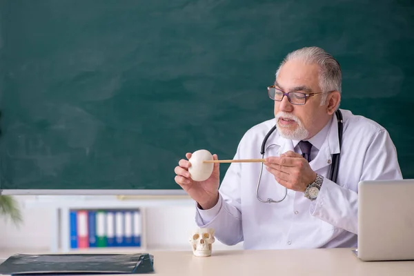 Oude mannelijke dokter leraar voor schoolbord — Stockfoto