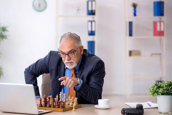 Viejo empresario jugando ajedrez en el lugar de trabajo — Foto de Stock