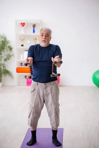 Starý muž dělá sportovní cvičení uvnitř — Stock fotografie