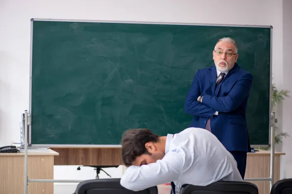 Viejo profesor masculino y joven estudiante masculino delante del tablero verde — Foto de Stock