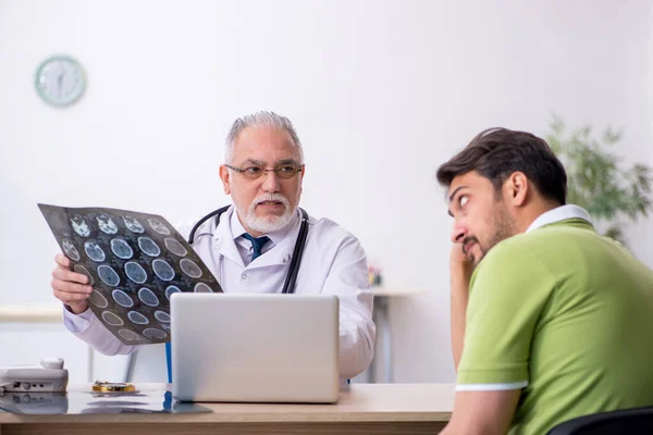 Hombre joven visitando viejo médico radiólogo —  Fotos de Stock