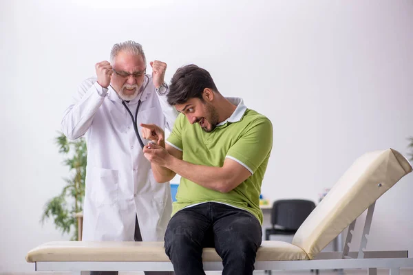 Giovane visitando vecchio medico maschio — Foto Stock