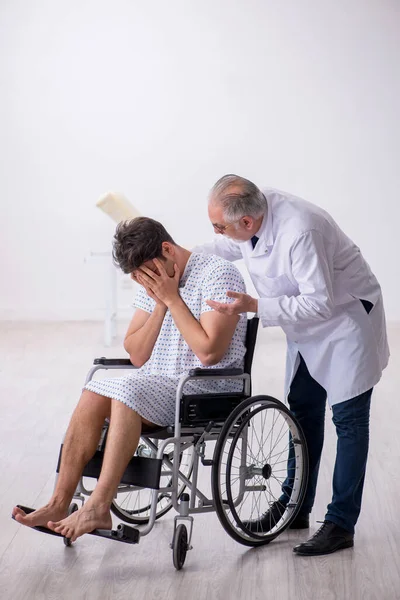 Old male doctor psychiatrist examining young disabled patient