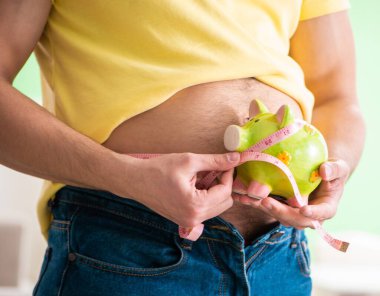 Diyet konseptiyle vücut yağlarını mezura ile ölçen adam.