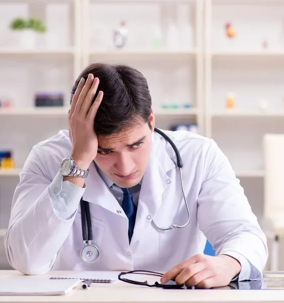 Junger Arzt sitzt im Büro — Stockfoto