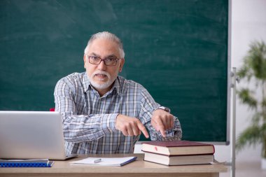 Sınıftaki yaşlı erkek öğretmen.