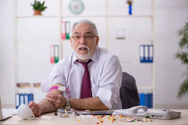 Alte drogenabhängige Angestellte sitzt im Büro — Stockfoto