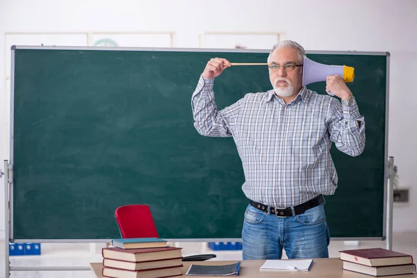 Velho professor do sexo masculino segurando megafone na sala de aula — Fotografia de Stock