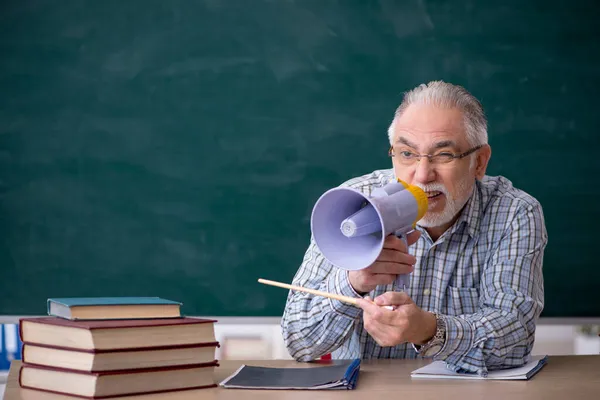 Alter männlicher Lehrer mit Megafon im Klassenzimmer — Stockfoto