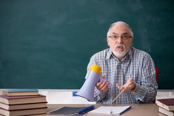 Velho professor do sexo masculino segurando megafone na sala de aula — Fotografia de Stock