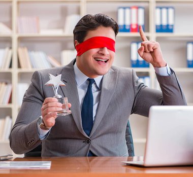 Ofiste masasında oturan gözü bağlı iş adamı.