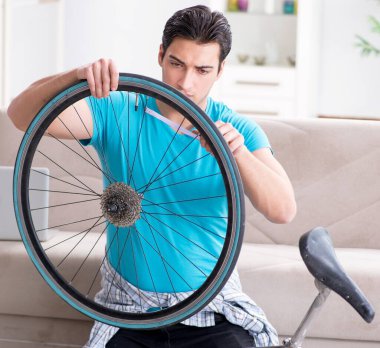 Evde bisiklet tamir eden genç bir adam.