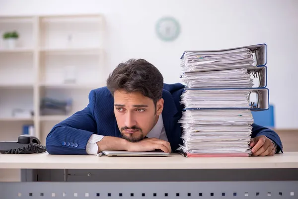 Joven empleado masculino y demasiado trabajo en la oficina — Foto de Stock