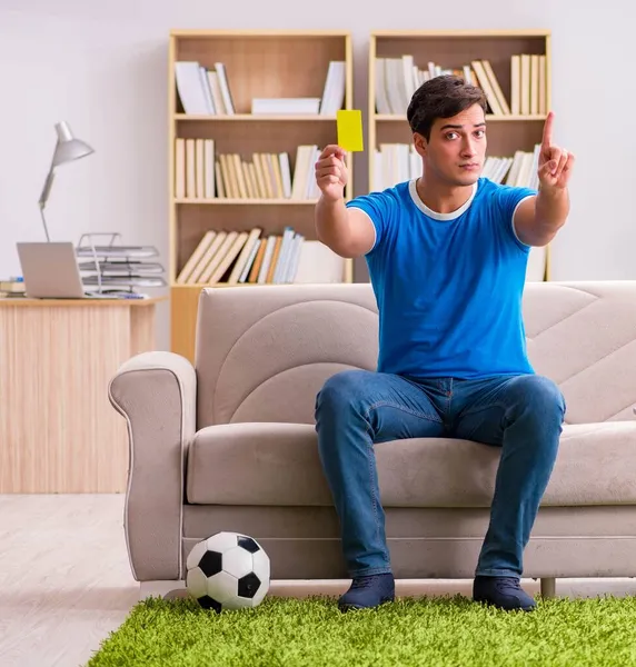 Homem assistindo futebol em casa sentado no sofá — Fotografia de Stock