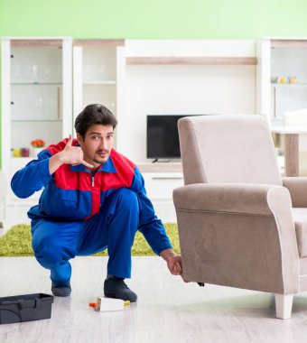 Müteahhit evde kırık mobilyaları tamir ediyor.