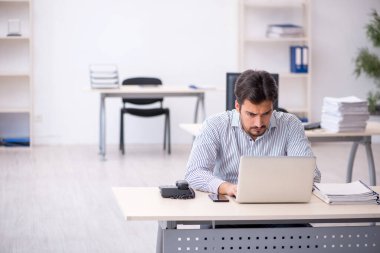 Genç bir erkek çalışan ve ofiste çok fazla iş var.