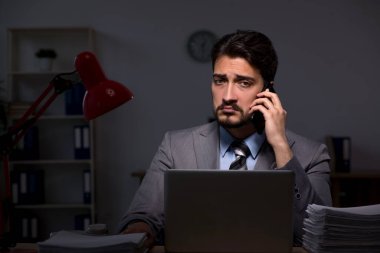 Genç erkek çalışan ofiste geç saatlere kadar çalışıyor.