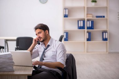 Genç bir erkek çalışan ve ofiste çok fazla iş var.