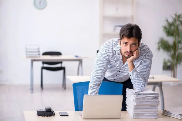 Joven empleado masculino y demasiado trabajo en la oficina —  Fotos de Stock