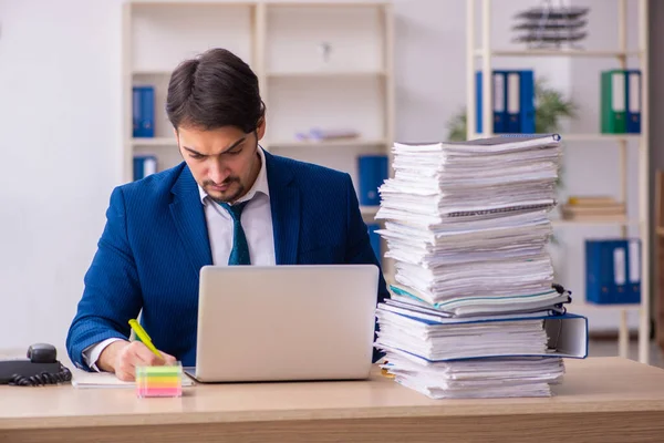 Jovem funcionário masculino e muito trabalho no escritório — Fotografia de Stock