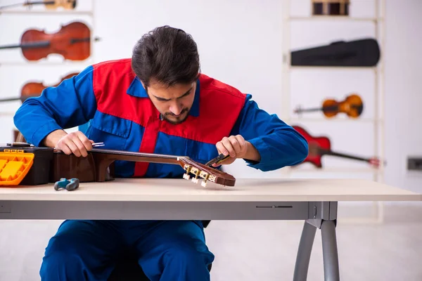 Giovane riparatore di sesso maschile che ripara strumenti musicali sul posto di lavoro — Foto Stock