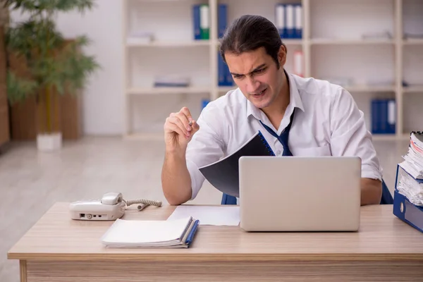 Jonge mannelijke werknemer en veel werk op kantoor — Stockfoto