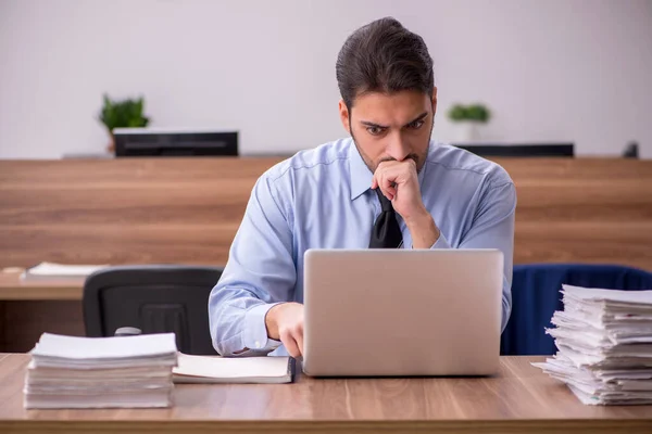 Ung manlig anställd och för mycket arbete på kontoret — Stockfoto