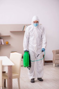 Young male contractor disinfecting at home