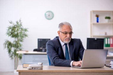 Ofiste çalışan yaşlı bir erkek.