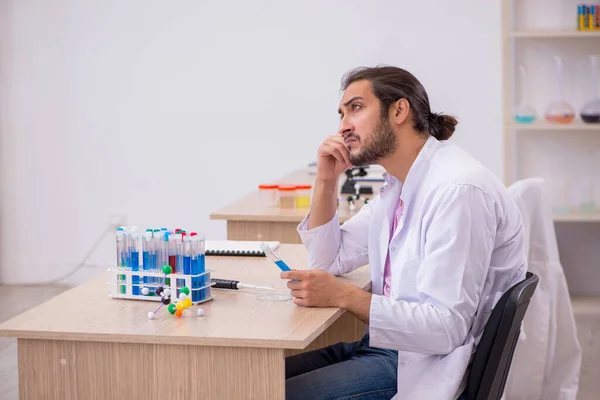 Молодий хімік чоловічої статі сидить за столом у класі — стокове фото