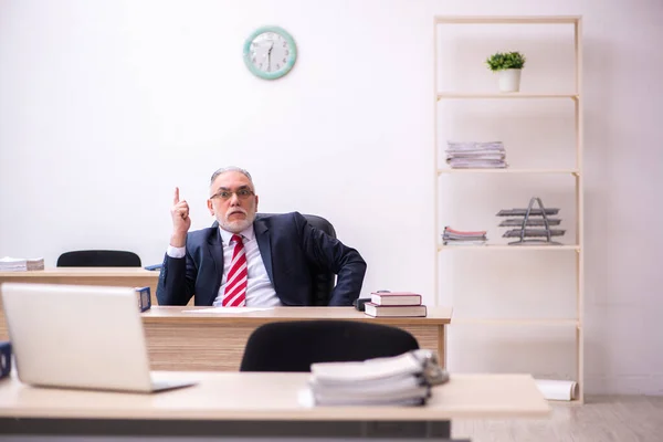 Старый бизнесмен сидит в офисе — стоковое фото