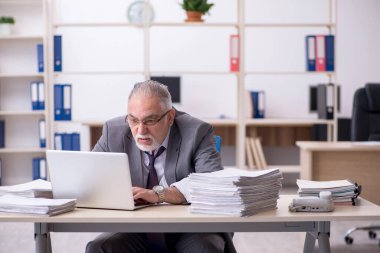 Ofisteki aşırı işten memnun olmayan yaşlı bir erkek işçi.