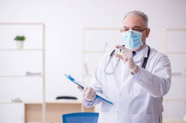 Klinikte çalışan yaşlı erkek doktor.