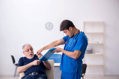 Yaşlı adam genç erkek doktoru ziyaret ediyor.