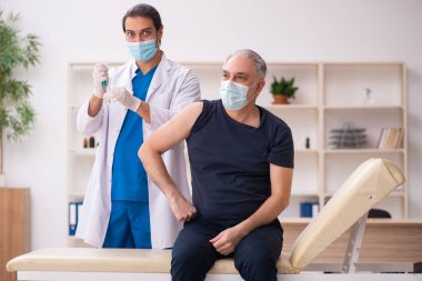 Yaşlı adam covid-19 aşı konseptinde genç doktoru ziyaret ediyor.