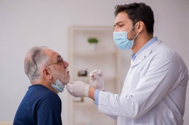 Yaşlı erkek hasta genç doktor otorhinolaryngologis 'i ziyaret ediyor.