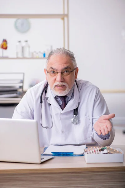 Gammal manlig läkare som arbetar på kliniken — Stockfoto