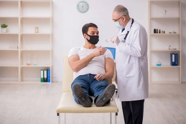 Молодой пациент посещает старого врача в концепции вакцинации — стоковое фото